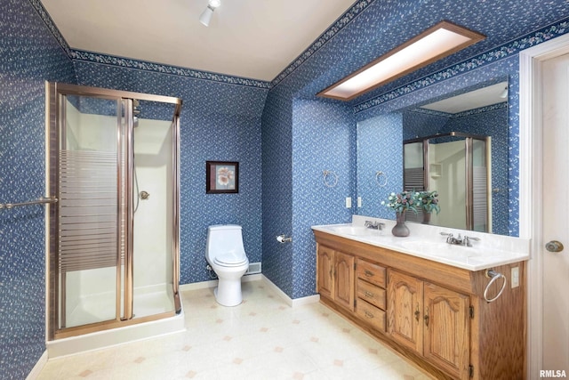 full bath featuring double vanity, wallpapered walls, toilet, a shower stall, and a sink