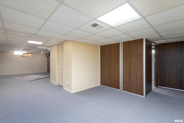 finished below grade area featuring visible vents, carpet, a paneled ceiling, and baseboards