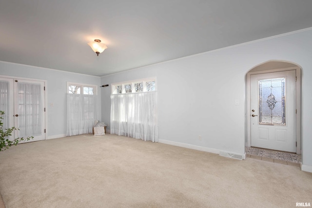 interior space featuring arched walkways, visible vents, crown molding, and baseboards