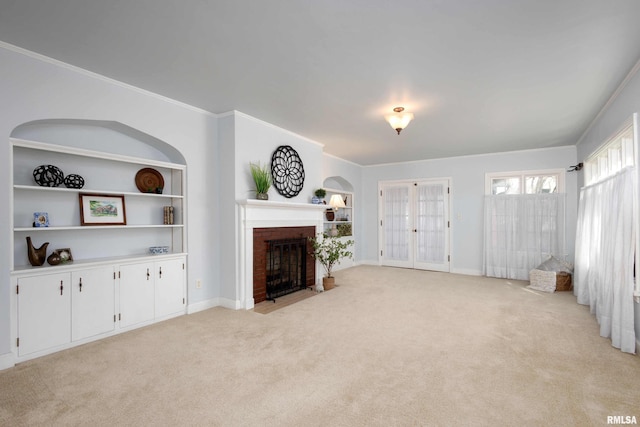 living area with built in shelves, light colored carpet, ornamental molding, a brick fireplace, and baseboards