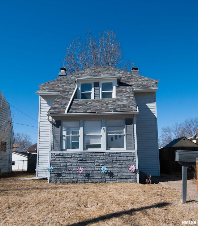 view of front facade featuring stone siding and a chimney