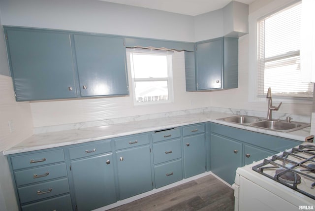 kitchen featuring blue cabinetry, white range with gas stovetop, and a sink