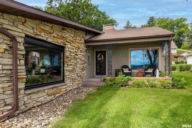 doorway to property with stone siding, a yard, and a chimney