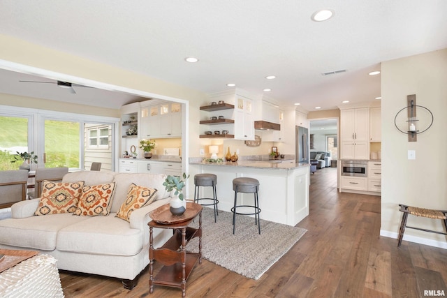 living area with baseboards, visible vents, dark wood-type flooring, and recessed lighting