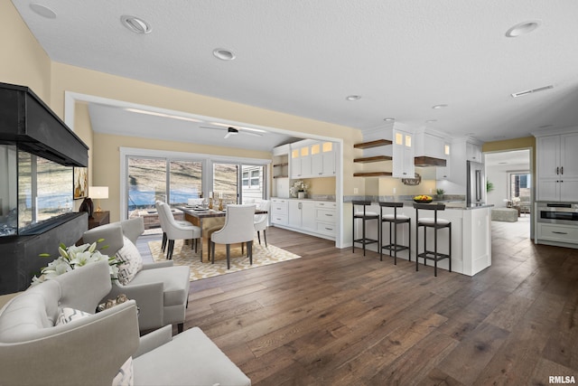 living area with a textured ceiling, dark wood-style flooring, visible vents, and recessed lighting