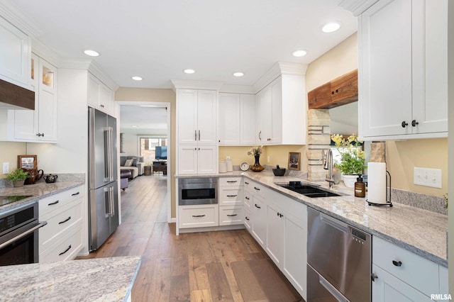 kitchen with light stone counters, stainless steel appliances, a sink, white cabinetry, and light wood-type flooring