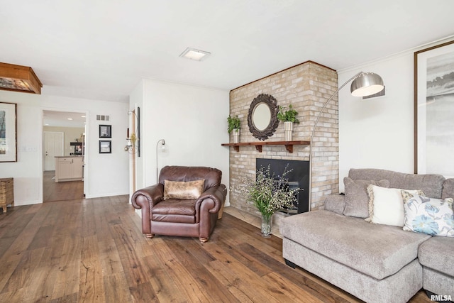 living area with hardwood / wood-style floors, a brick fireplace, and visible vents