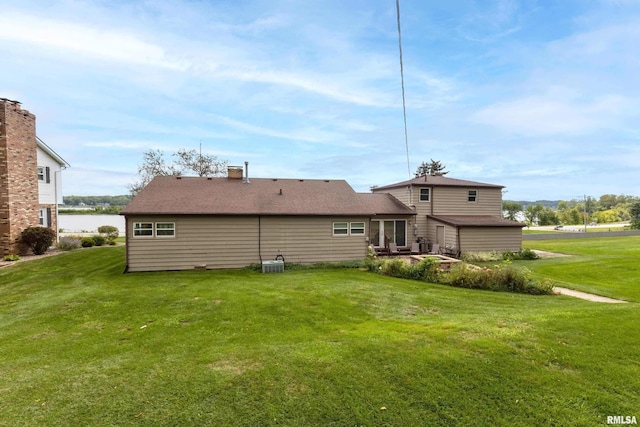 back of house with a chimney, central AC unit, and a lawn