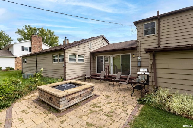 rear view of house with a fire pit, central AC, and a patio