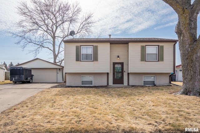 split foyer home with an outbuilding, brick siding, a detached garage, and a front yard