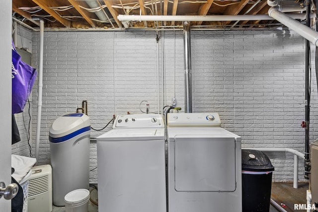 laundry room featuring laundry area, brick wall, and independent washer and dryer