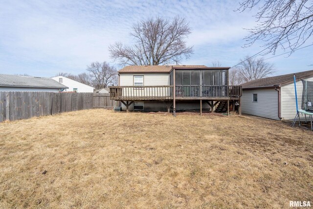 rear view of house with a trampoline, an outbuilding, a lawn, a sunroom, and a fenced backyard