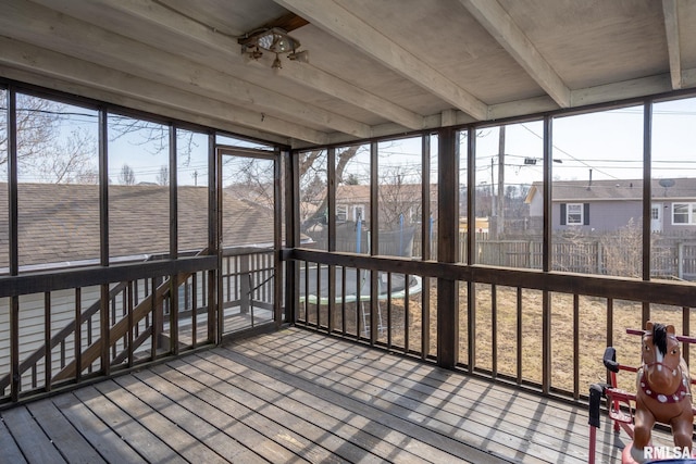 unfurnished sunroom featuring beam ceiling and plenty of natural light