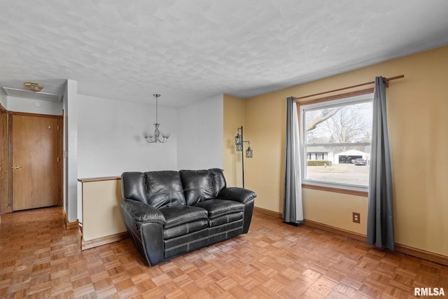 living room featuring a textured ceiling, a chandelier, and baseboards