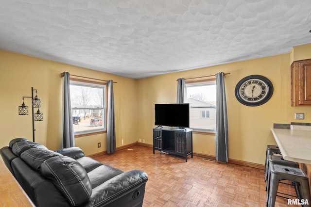 living room with a healthy amount of sunlight, baseboards, and a textured ceiling