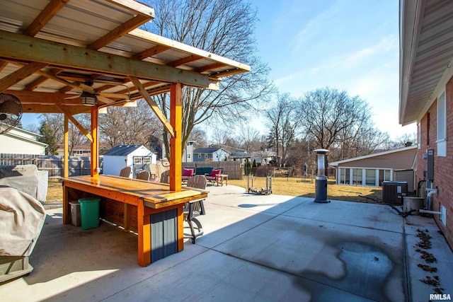 view of patio / terrace featuring outdoor dining space, a fenced backyard, an outdoor structure, and central air condition unit