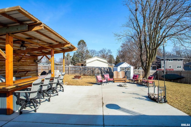 view of patio / terrace with a fire pit, a storage unit, an outbuilding, and a fenced backyard