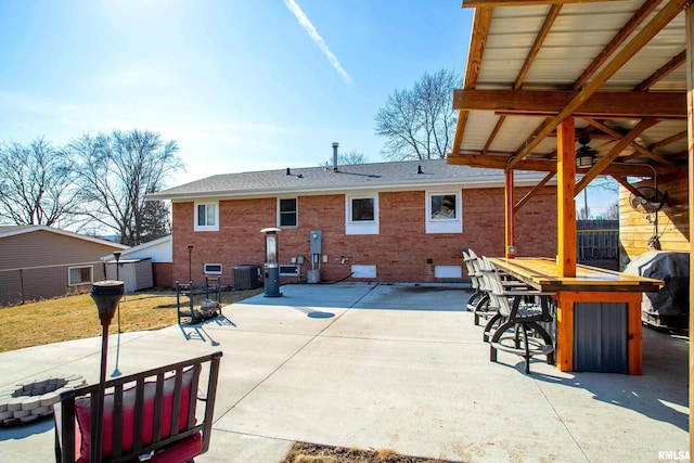 rear view of house featuring a shingled roof, central AC unit, a patio, and brick siding