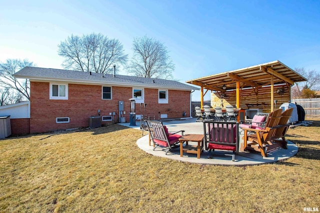 rear view of property featuring brick siding, a lawn, a patio area, fence, and cooling unit