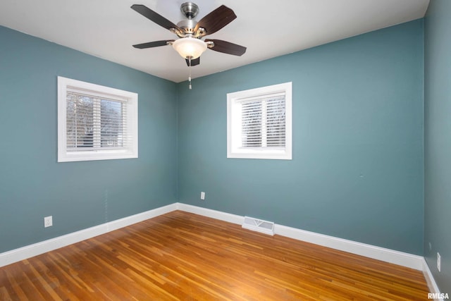 unfurnished room featuring baseboards, visible vents, ceiling fan, and wood finished floors