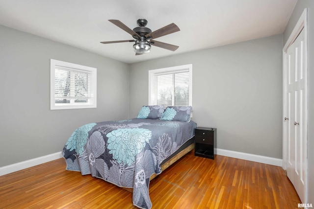 bedroom with a closet, wood finished floors, and baseboards