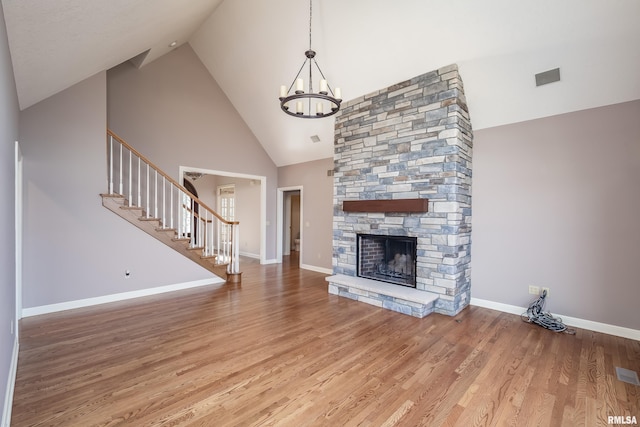 unfurnished living room with a fireplace, a chandelier, light wood-type flooring, baseboards, and stairs