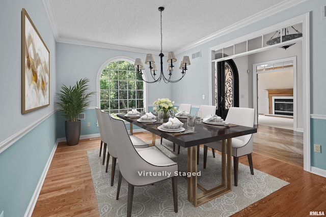 2 S Shore Ln, Rapids City, IL 61278 - dining space featuring a chandelier, crown molding, light wood-type flooring, and a textured ceiling