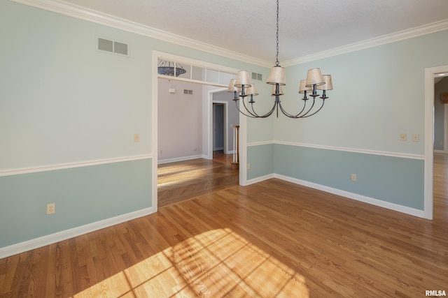 unfurnished dining area with wood finished floors, visible vents, baseboards, an inviting chandelier, and crown molding