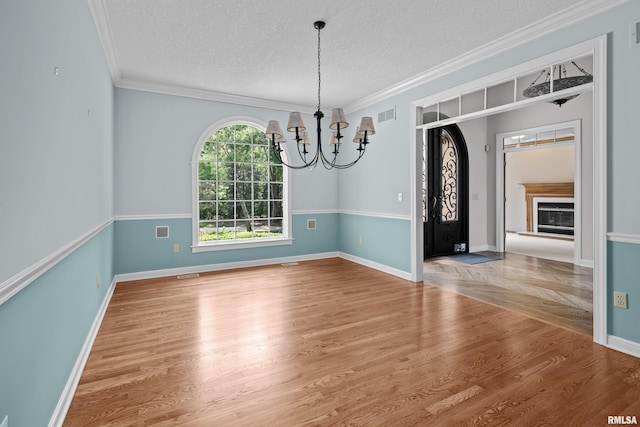 2 S Shore Ln, Rapids City, IL 61278 - unfurnished dining area featuring a chandelier, wood finished floors, a textured ceiling, crown molding, and a glass covered fireplace