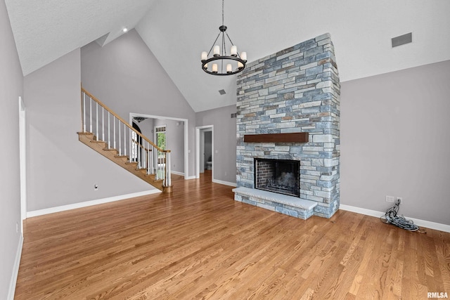 2 S Shore Ln, Rapids City, IL 61278 - unfurnished living room with high vaulted ceiling, a chandelier, wood finished floors, stairs, and a fireplace