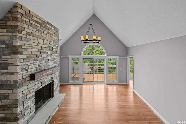 2 S Shore Ln, Rapids City, IL 61278 - unfurnished living room featuring wood finished floors, a fireplace, a chandelier, high vaulted ceiling, and a textured ceiling