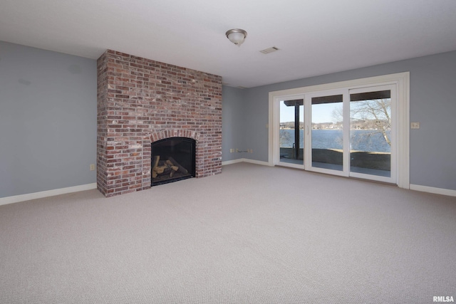 unfurnished living room with a water view, baseboards, a fireplace, and visible vents