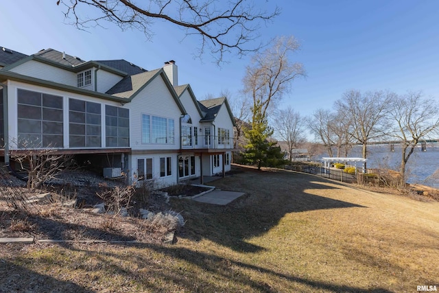 back of house with central AC unit, a lawn, a chimney, and a sunroom