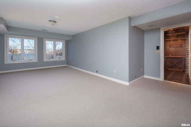 carpeted spare room with a textured ceiling and baseboards