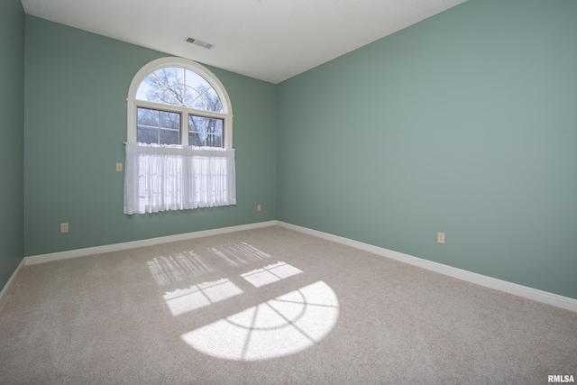 carpeted empty room featuring visible vents and baseboards