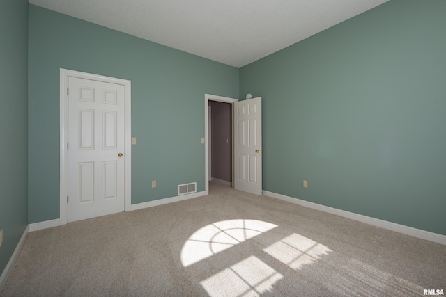 unfurnished bedroom with baseboards, visible vents, and light colored carpet