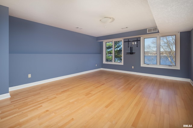 empty room featuring light wood-style floors, visible vents, and baseboards