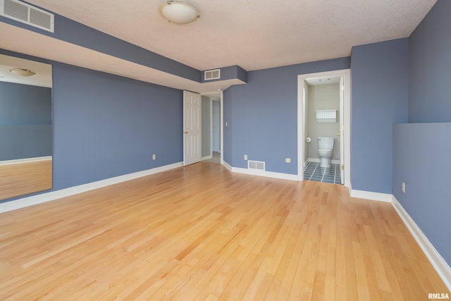 empty room featuring wood finished floors, visible vents, and baseboards