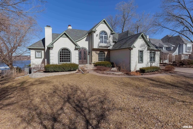 view of front of home featuring a front yard, a chimney, fence, and stucco siding