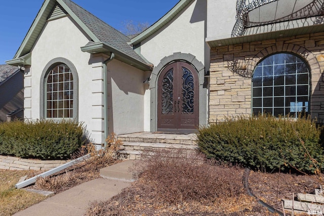 view of exterior entry featuring roof with shingles and stucco siding