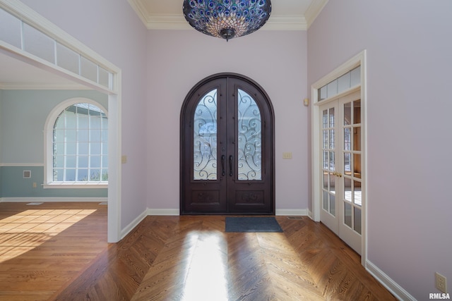 entrance foyer featuring baseboards, arched walkways, ornamental molding, and french doors