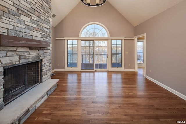 unfurnished living room with baseboards, a fireplace, high vaulted ceiling, and wood finished floors