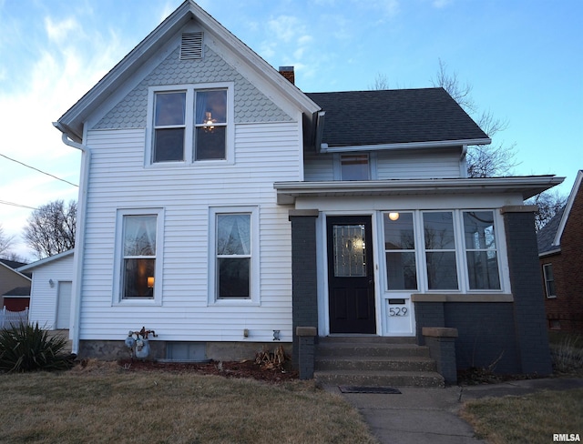 view of front of home featuring entry steps, a chimney, and a front yard