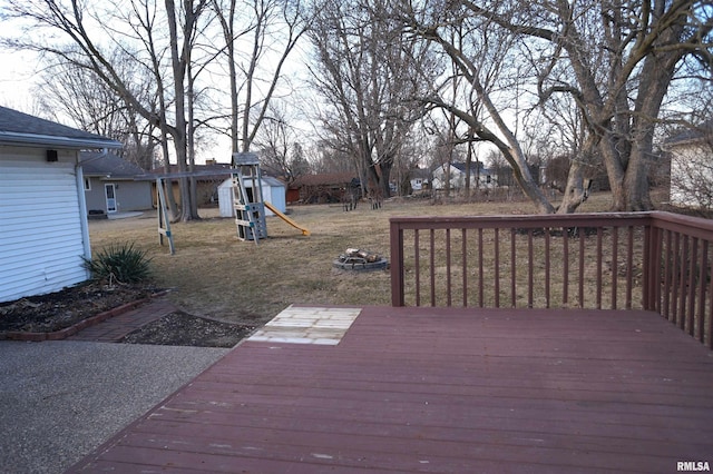 wooden deck with a fire pit, a yard, and a playground