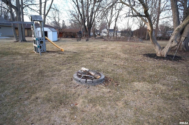 view of yard with a storage unit, a fire pit, and an outbuilding