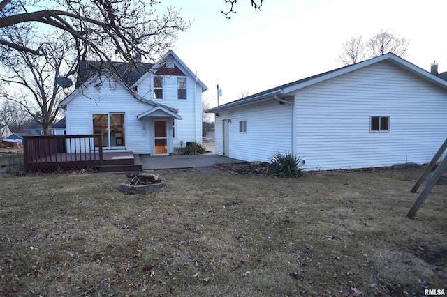 rear view of property featuring an outdoor fire pit, a yard, and a deck