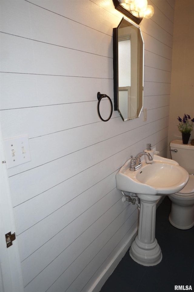 half bathroom featuring wooden walls and toilet