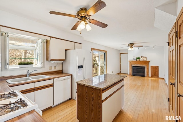 kitchen featuring decorative backsplash, light wood-style floors, white cabinets, a sink, and white appliances