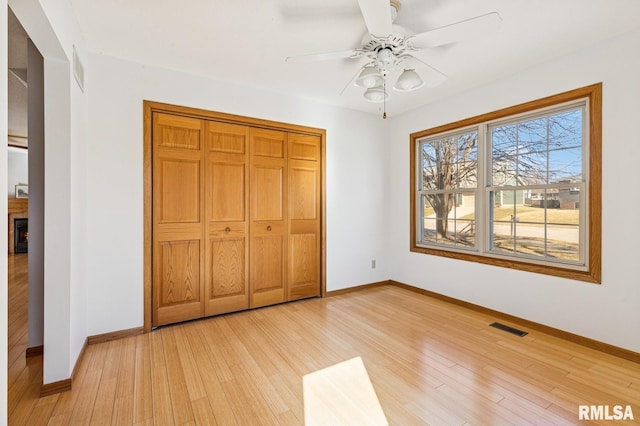 unfurnished bedroom featuring a closet, visible vents, light wood-style flooring, and baseboards