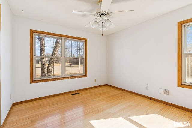 spare room featuring visible vents, light wood finished floors, a wealth of natural light, and baseboards